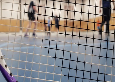 Badminton net with blurred players in indoor court