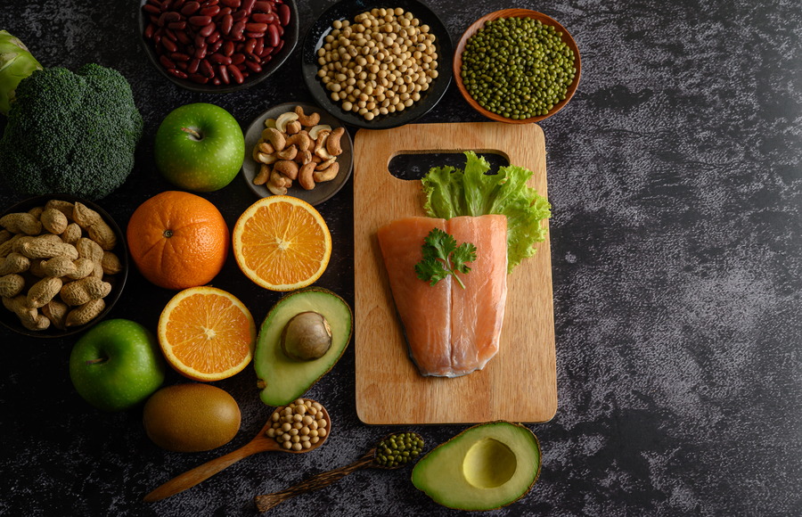 High-protein foods like lentils, beans, broccoli, and avocado arranged on a table.