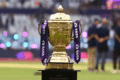 IPL trophy with colorful fan decorations and blurred stadium background
