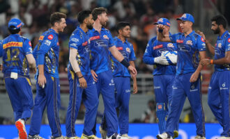 Cricket players in blue jerseys standing together on the field.