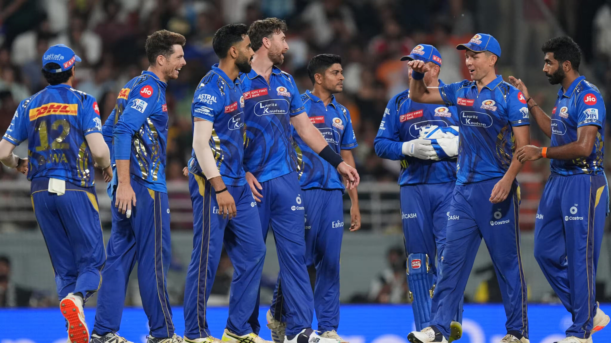 Cricket players in blue jerseys standing together on the field.