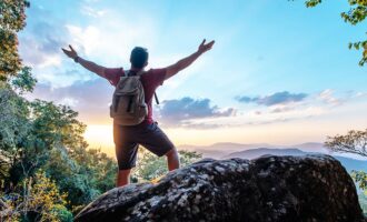 A traveler standing on mountain peak, enjoying scenic view