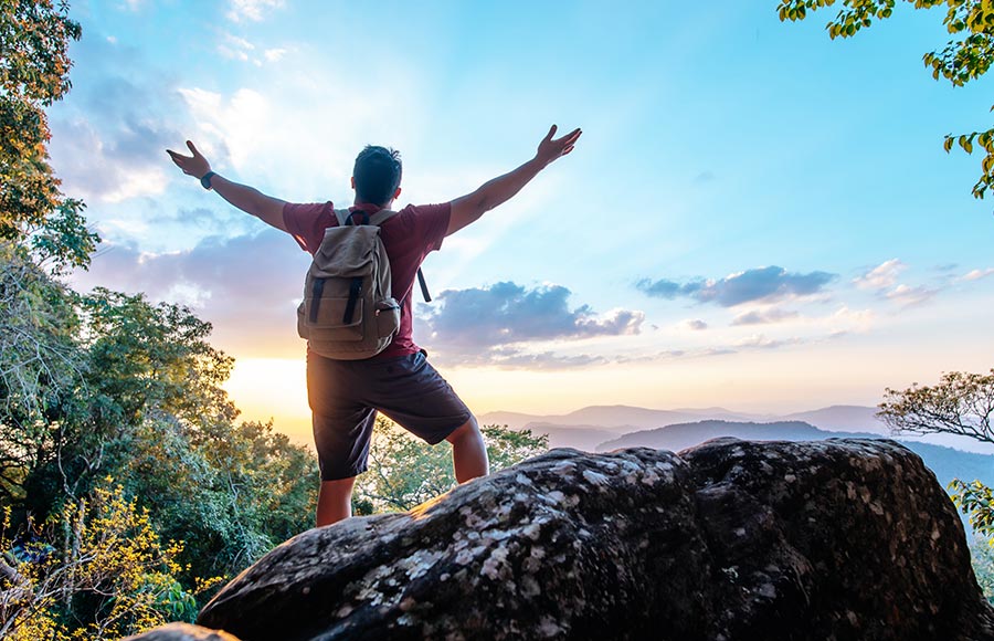 A traveler standing on mountain peak, enjoying scenic view
