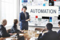 Professional presenting automation strategy to team in meeting room with charts and data visuals