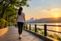 A woman walking along a lakeside pathway at sunset, illustrating the benefits of daily walking, outdoor exercise and a healthy lifestyle.